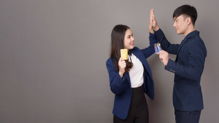 portrait of young Asian business people  holding credit card on gray studio backgroundの写真素材