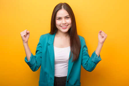 Beautiful woman in green suit happy on yellow backgroundの写真素材