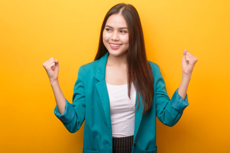Beautiful woman in green suit happy on yellow backgroundの写真素材