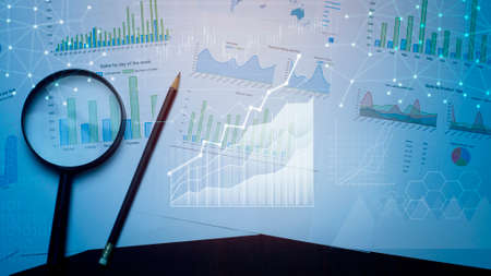 Magnifying glass and documents with analytics data lying on table