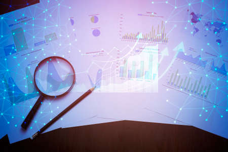 Magnifying glass and documents with analytics data lying on table
