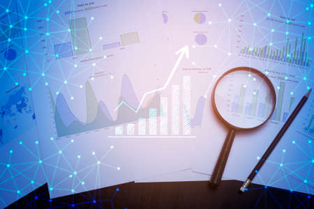 Magnifying glass and documents with analytics data lying on table