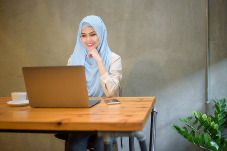 Muslim woman with hijab is working with laptop computer in coffee shopの写真素材