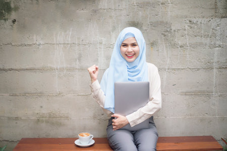 Muslim woman with hijab is working with laptop computer in coffee shop
