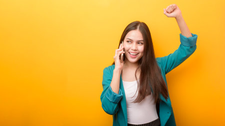 Fashion portrait of beautiful woman in green suit  using cellphone on yellow backgroundの写真素材
