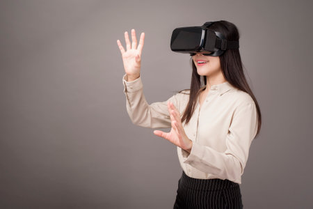 beautiful woman is using virtual reality on gray background