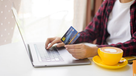 Beautiful woman is online shopping with credit card in coffee shopの写真素材