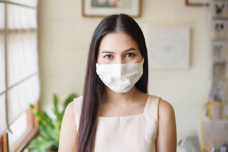 Beautiful young Woman with face mask is sitting in coffee shopの写真素材