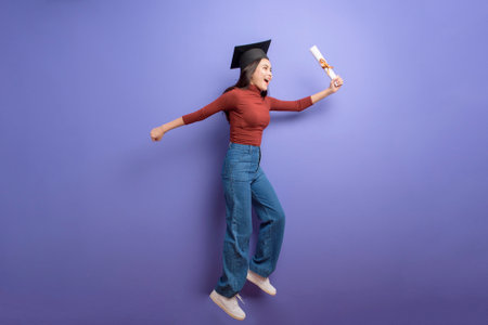 Portrait of young University student woman with graduation cap on violet background