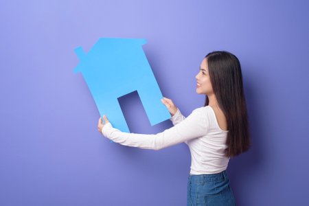 Portrait of beautiful woman  is holding blue  home on purple backgroundの写真素材