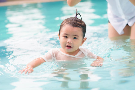 A Happy Asian mother and daughter are enjoy swimming in pool , lifestyle, parenthood, family concept...