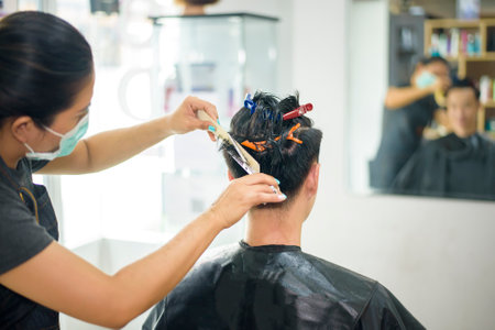 a young man is getting a haircut in a hair salon, Salon safety conceptの写真素材