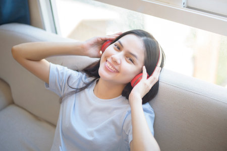 a young woman is using headset enjoying with music in living room , home safety concept.の写真素材
