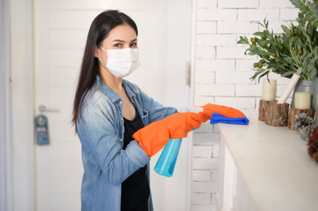A woman with cleaning gloves using alcohol spray sanitiser to cleaning house, healthy and medical