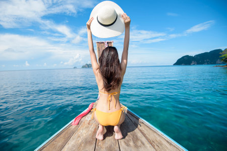 View of woman in swimsuit enjoying on thai traditional longtail Boat over beautiful mountain and ocean, Phi phi Islands, Thailandの写真素材