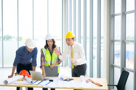Engineering people are analytics construction plans with blueprint in office .