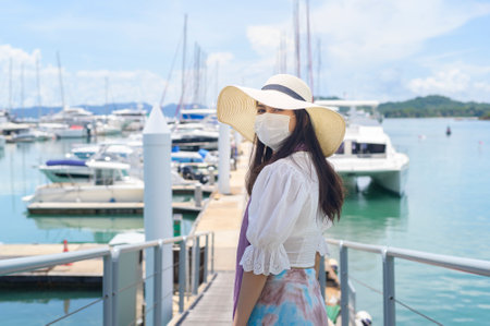 A traveler woman is wearing protective mask in on the dock, travel under pandemic, safety travels, social distancing protocol, New normal travel conceptの写真素材