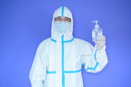An Asian man is wearing ppe suit on purple background .