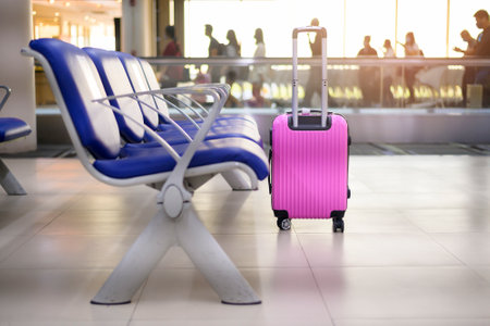 A pink suitcase in departure terminal at the airportの写真素材