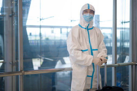 An Asian man is wearing ppe suit in airport elevator , Safety travel , covid-19 protection , social distancing concept .の写真素材