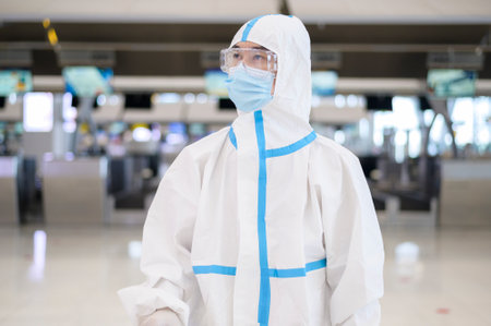 An Asian man is wearing ppe suit in International airport , Safety travel , covid-19 protection , social distancing concept .の写真素材