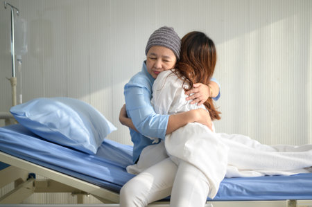 A cancer patient woman wearing head scarf hugging her supportive daughter indoors, health and insurance concept.の写真素材