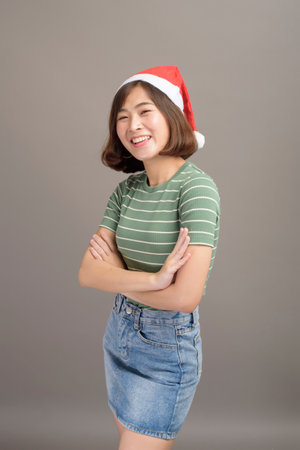 A portrait of beautiful woman wearing red Santa Claus hat holding gift box over studio background, Christmas conceptの写真素材