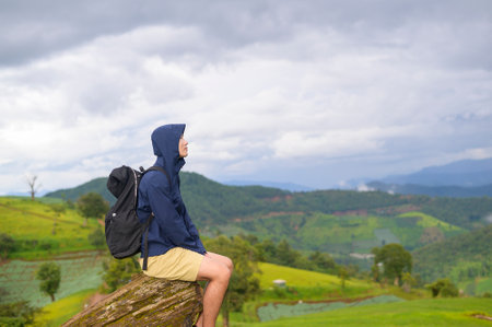 A traveling man enjoying and relaxing over beautiful green mountain view in rain season, Tropical climate.の写真素材