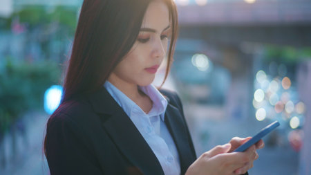 A young business woman wearing black suit is using smart phone , in the city, Business Lifestyle Concept.の写真素材