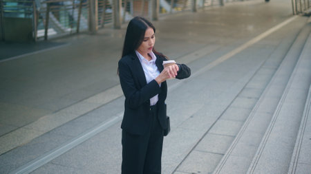 A young business woman wearing black suit hurry up during morning rush hour, holding a cup of coffee walking in the city, Business Lifestyle Concept.の写真素材