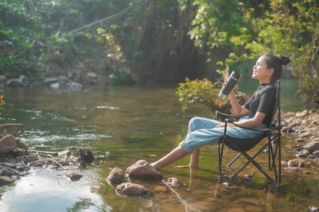 A beautiful young traveler woman is enjoying with nature drinking coffee in the morning over lake, relaxation , camping holiday and travel concept .の写真素材