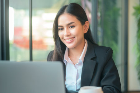 A beautiful business woman is analyzing financial data via computer , drinking coffee in coffee shop . business people lifestyle . technology concept .の写真素材