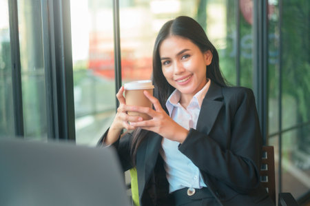 A beautiful business woman is analyzing financial data via computer , drinking coffee in coffee shop . business people lifestyle . technology concept .の写真素材