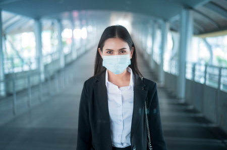 Young business woman with face mask  is standing on metro platform using smart.の写真素材