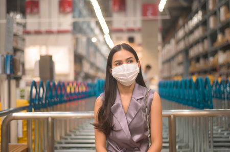 Portrait of young pretty woman wearing a surgical mask in shopping mall,  pandemic concept.の写真素材