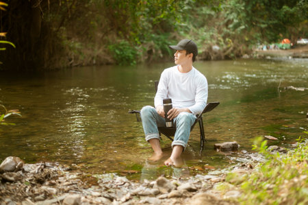 A man is sitting over lake , enjoying with nature and coffee , travel relaxation concept.の写真素材
