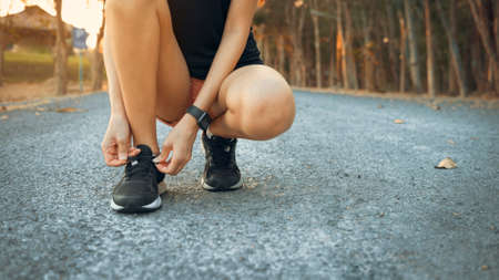 A young woman is doing Tie shoelaces before running in nature outdoor