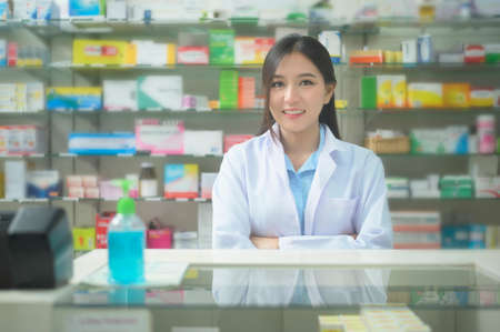 A portrait of asian woman pharmacist wearing lab coat in a modern pharmacy drugstore.の写真素材