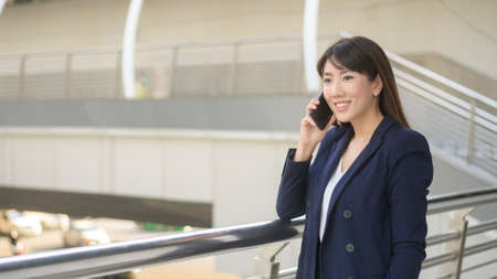 beautiful young asian business woman is using smartphone in modern cityの写真素材