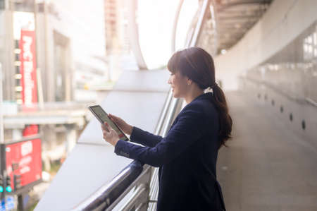 beautiful young asian business woman is using tablet in modern cityの写真素材