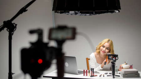 Behind the scenes young blonde woman entrepreneur working with laptop presents cosmetic products...