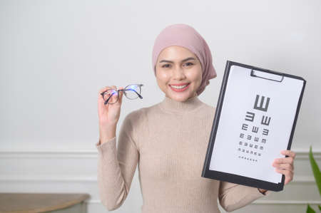 A young muslim woman holding a vision chart test for measuring visual acuityの写真素材