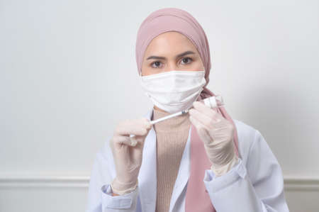 A young female muslim doctor holding a syringe with   vaccine bottle for injection,   vaccination and health care conceptの写真素材