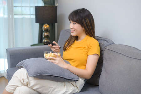 A young happy woman watching movie and relaxing at home