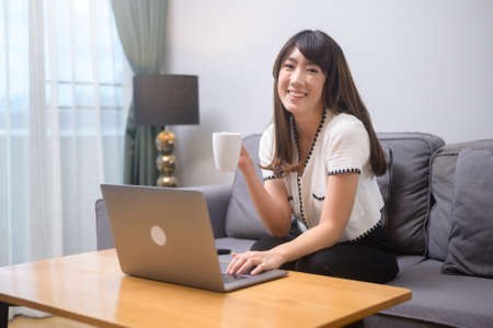 A young female working with her laptop and having a cup of coffee, life style and business conceptの写真素材
