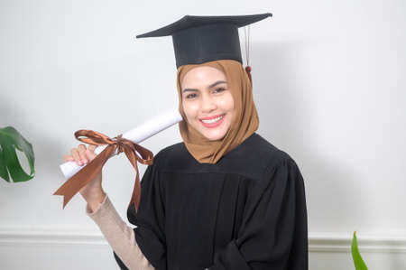 A young muslim woman graduated holding a certification.