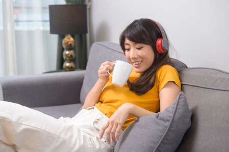 A young happy woman listening to music and relaxing at home