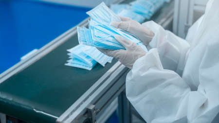 Close up of worker producing surgical mask in modern factory,   protection and medical concept.の写真素材