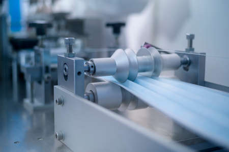 Close up of machine producing surgical mask in modern factory,  protection and medical concept.