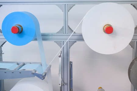 Close up of machine producing surgical mask in modern factory,   protection and medical concept.の写真素材